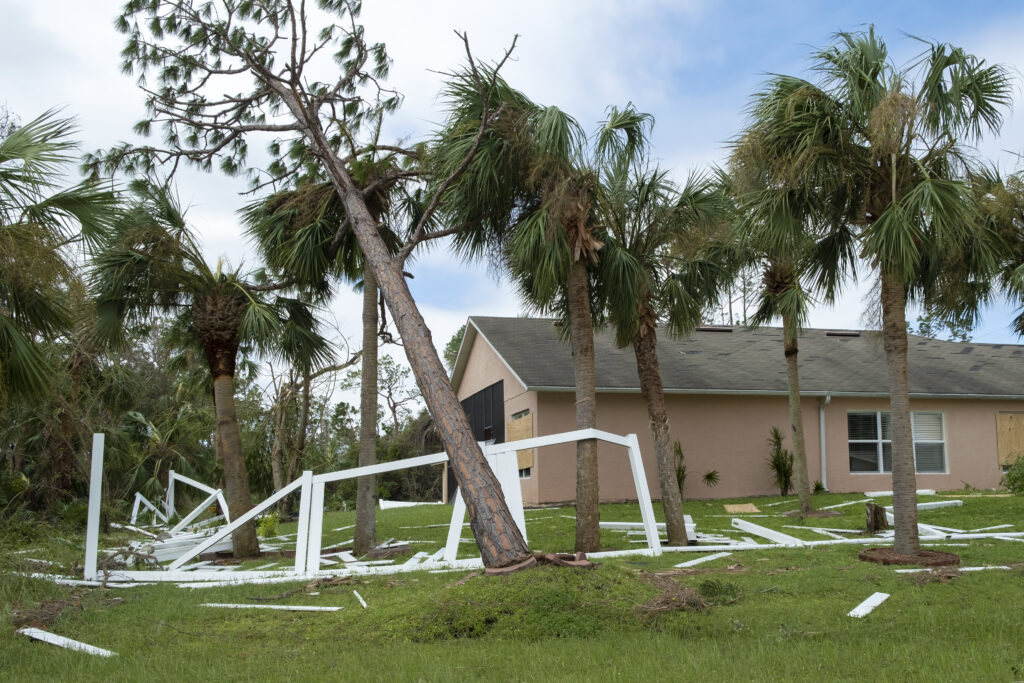 Hurricane damage to white PVC backyard fence ruined after tree debris fell down on it in Florida.